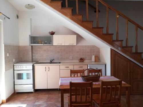 eine Küche mit weißen Schränken und einem Tisch mit Stühlen in der Unterkunft Apartment Kukljica 8209a in Kukljica
