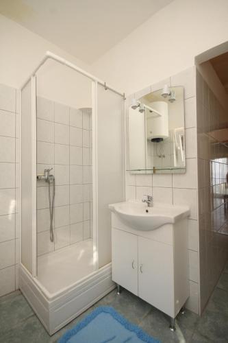 a white bathroom with a sink and a shower at Apartments by the sea Ugljan - 8257 in Ugljan
