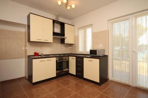 cocina con armarios blancos y fogones en Apartments by the sea Ugljan - 8257 en Ugljan