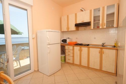 une cuisine avec un réfrigérateur blanc et une fenêtre dans l'établissement Apartments by the sea Kali, Ugljan - 8235, à Kali
