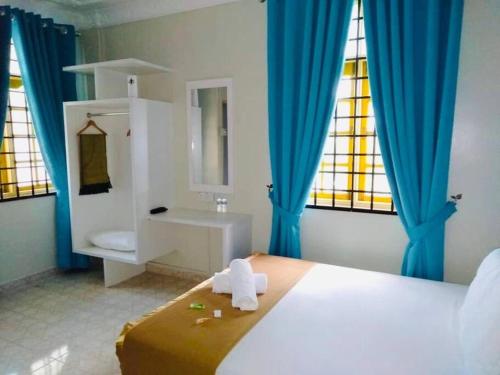 1 dormitorio con cama, lavabo y cortinas azules en Irama Banglo with Private Pool, en Bachok