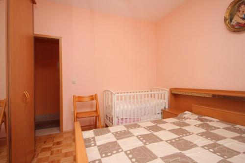 a bedroom with a bed and a crib and a chair at Apartment Kraj 8288a in Kraj