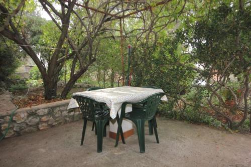 a table with two chairs in a park with trees at Apartments by the sea Ugljan - 8519 in Ugljan