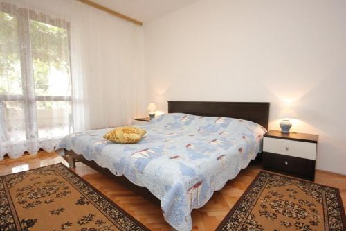 a bedroom with a bed with a blue comforter and two rugs at Apartments by the sea Muline, Ugljan - 8520 in Donje Selo