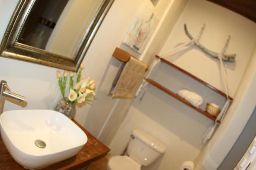 La salle de bains est pourvue d'un lavabo, de toilettes et d'un miroir. dans l'établissement Sirena Surf Lodge Miramar Nicaragua, à Miramar