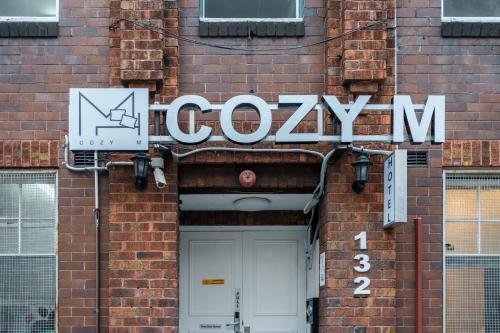 un letrero para un gimnasio al lado de un edificio de ladrillo en Cozy M Hotel, en Sídney