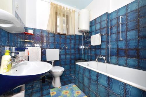 a blue tiled bathroom with a toilet and a sink at Apartments by the sea Arbanija, Ciovo - 8651 in Trogir