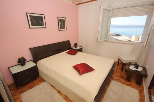 een slaapkamer met een bed met een rood kussen erop bij Apartments with a parking space Dugi Rat, Omis - 8666 in Dugi Rat