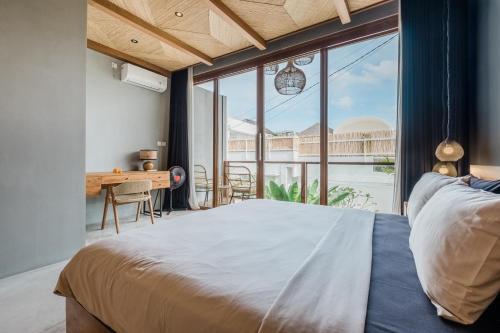 Schlafzimmer mit einem Bett, einem Schreibtisch und einem großen Fenster in der Unterkunft Zazen 2 Villa by Hombali in Canggu