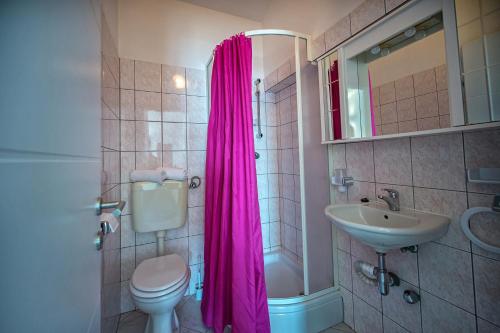uma casa de banho com uma cortina de chuveiro rosa e um lavatório. em Studio Zecevo Rtic 8366a em Rogoznica