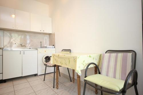 uma cozinha com uma mesa e cadeiras numa cozinha em Apartments by the sea Duce, Omis - 8680 em Duće