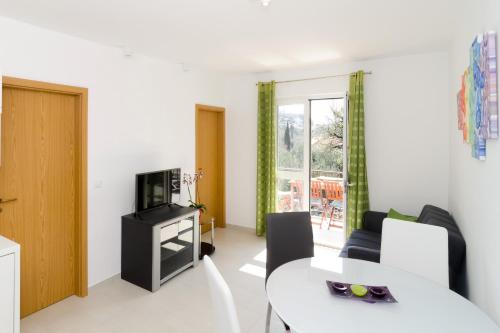 ein Wohnzimmer mit einem Tisch und einem TV in der Unterkunft Apartments with a parking space Mlini, Dubrovnik - 8542 in Mlini