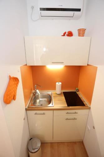 a small kitchen with a sink and an orange wall at Apartments by the sea Pag - 6475 in Pag