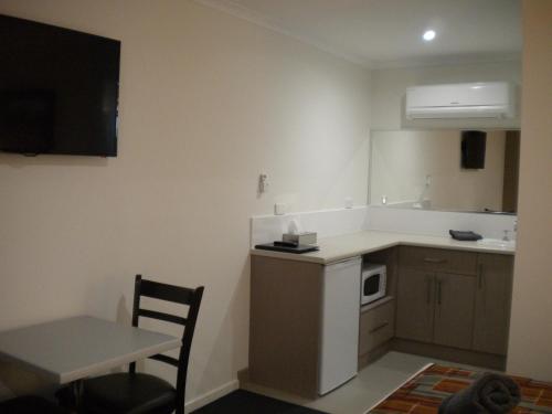 a small kitchen with a table and a microwave at Moama Central Motel in Echuca