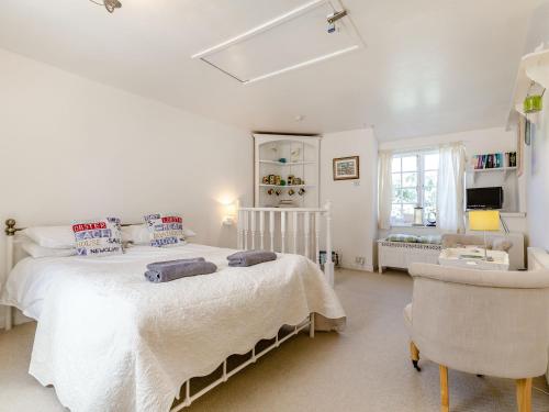 a bedroom with a large white bed and a chair at Sea View in Penzance