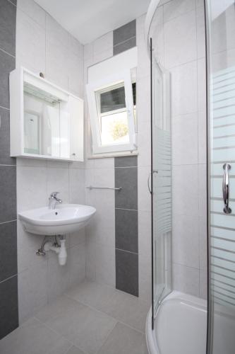 a white bathroom with a sink and a shower at Apartments by the sea Basina, Hvar - 8754 in Vrbanj