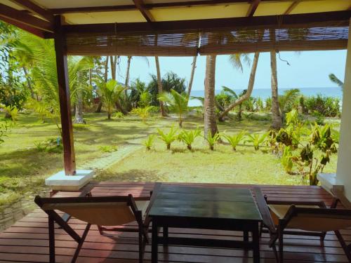 a table and chairs on a porch with a view of the ocean at Emerald Sea Resort in Ngwesaung