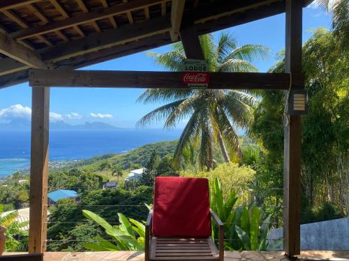 a red chair sitting on a porch overlooking the ocean at Globe trotter Lodge Tahiti in Punaauia