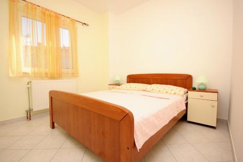 ein Schlafzimmer mit einem Holzbett und einem Fenster in der Unterkunft Apartment Okrug Gornji 8440c in Trogir