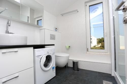 a white bathroom with a washing machine and a window at Apartments by the sea Zecevo Rtic, Rogoznica - 10333 in Rogoznica