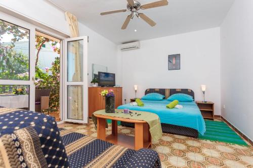 Schlafzimmer mit einem blauen Bett und einem Tisch in der Unterkunft Rooms by the sea Mavarstica, Ciovo - 10335 in Trogir