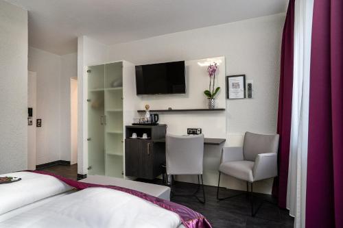 a hotel room with a desk and a tv at Hotel Stadt Heidelberg in Darmstadt