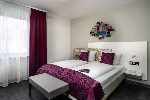 a bedroom with a large white bed with purple sheets at Hotel Stadt Heidelberg in Darmstadt