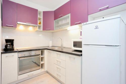 cocina con armarios morados y nevera blanca en Apartments with a parking space Omis - 10362, en Omiš
