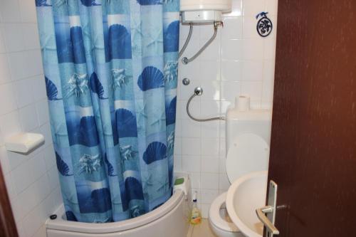 ein Badezimmer mit einem blauen Duschvorhang und einem WC in der Unterkunft Apartments by the sea Arbanija, Ciovo - 11041 in Trogir