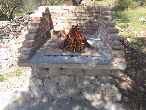 a brick fireplace with a fire in it at Seaside secluded apartments Cove Krsovica - Telascica, Dugi otok - 11001 in Sali
