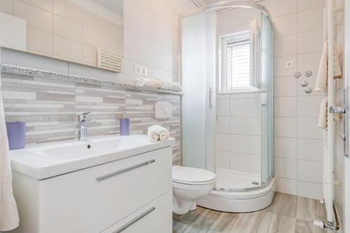 a white bathroom with a toilet and a sink at Apartments by the sea Slatine, Ciovo - 11047 in Slatine