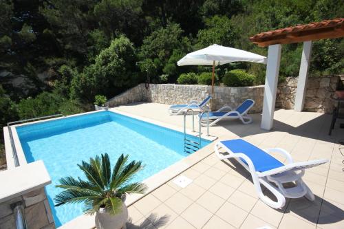 a swimming pool with two chairs and an umbrella at Family friendly apartments with a swimming pool Trstenik, Peljesac - 11081 in Trstenik