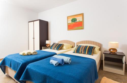 two beds in a room with blue sheets and towels at Family friendly apartments with a swimming pool Trstenik, Peljesac - 11081 in Trstenik