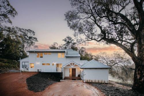 Una casa blanca con un árbol delante. en Ampersand Estates, en Pemberton