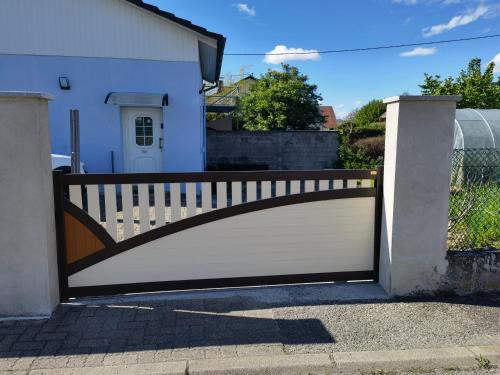 une clôture blanche avec un portail en face d'une maison dans l'établissement MAISON COSY 7 minutes des frontières, à Rosenau