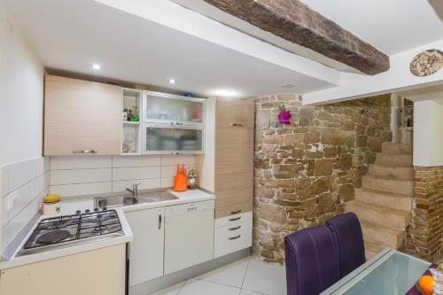 uma cozinha com armários brancos e uma parede de pedra em Seaside holiday house Kastel Stafilic, Kastela - 11165 em Kaštela