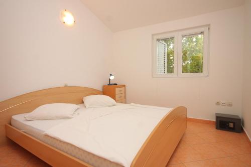 Schlafzimmer mit einem großen weißen Bett und einem Fenster in der Unterkunft Family friendly seaside apartments Preko, Ugljan - 8232 in Poljana
