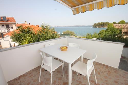 einen weißen Tisch und Stühle auf einem Balkon mit Blick auf das Wasser in der Unterkunft Family friendly seaside apartments Preko, Ugljan - 8232 in Poljana