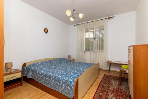 a bedroom with a bed and a table and a window at Apartment Supetar 11278a in Supetar