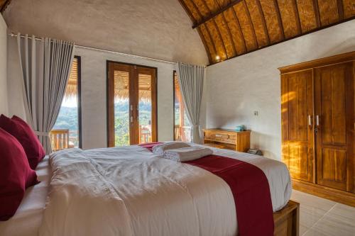 um quarto com uma cama grande e uma janela em Alit Cottage em Nusa Penida