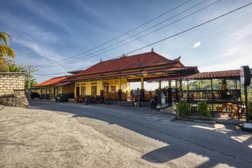 a yellow building with a red roof next to a street at Alit Cottage in Nusa Penida