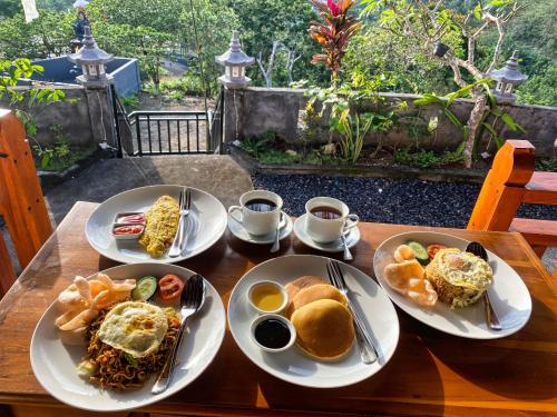 three plates of food on a wooden table at Alit Cottage in Nusa Penida