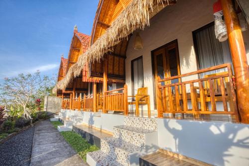 a building with a porch and chairs on it at Alit Cottage in Nusa Penida