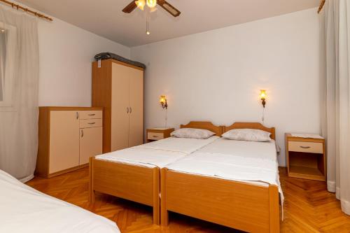 una camera con 2 letti e un ventilatore a soffitto di Apartments with a parking space Supetar, Brac - 11278 a Supetar (San Pietro di Brazza)