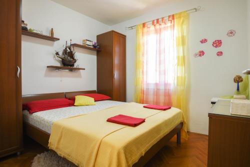 a bedroom with a bed with two red pillows on it at Apartments by the sea Splitska, Brac - 11300 in Splitska