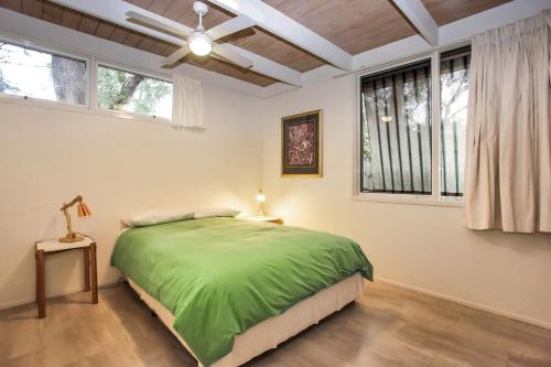 a bedroom with a green bed and two windows at Sandy Shores in Hawks Nest