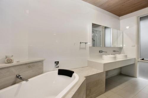 a white bathroom with a tub and a sink at Sandy Shores in Hawks Nest