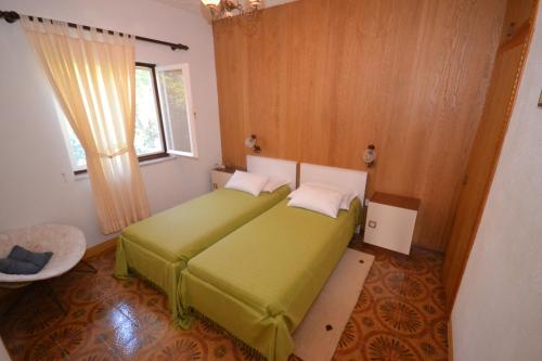 a bedroom with a green bed and a window at Apartments by the sea Splitska, Brac - 11339 in Splitska
