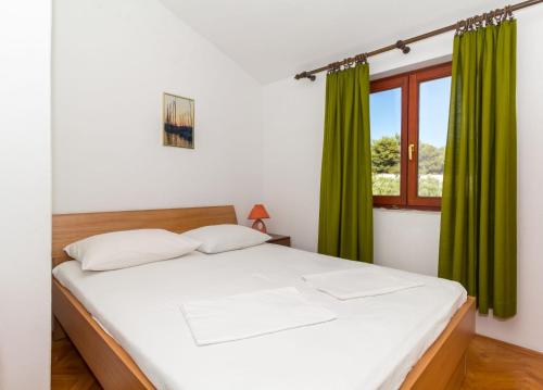 Schlafzimmer mit einem Bett mit grünen Vorhängen und einem Fenster in der Unterkunft Apartments with a parking space Biograd na Moru, Biograd - 11327 in Biograd na Moru
