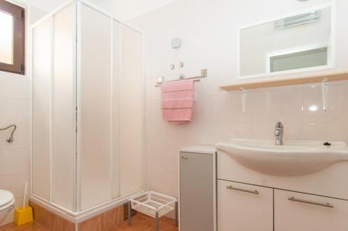 a white bathroom with a sink and a shower at Apartments with a parking space Mali Losinj (Losinj) - 11344 in Mali Lošinj